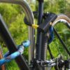 Fahrrad am Hinterrad, Vorderrad und Fahrradrahmen mit D-lock Bügelschloss und eyelet-Textilseil in morpho blue am Fahrradständer angeschlossen