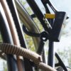D-lock Bügelschloss sichert Fahrrad mit Textilseil in wild hemp am Oberrohr an Fahrradständer