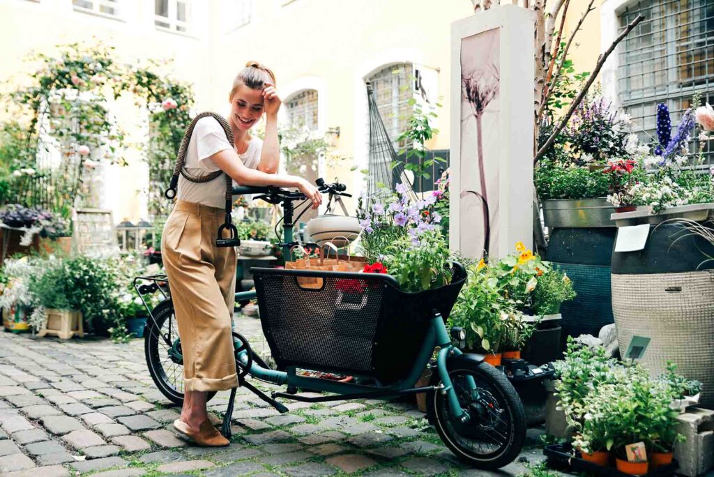 Junge Frau mit beladenem Lastenrad und tex–lock eyelet um der Schulter