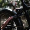 Schwarzes Fahrrad mit Rahmenschloss und Verlängerung tex–lock mate in chateau red um einen Pfeiler in der Natur angeschlossen