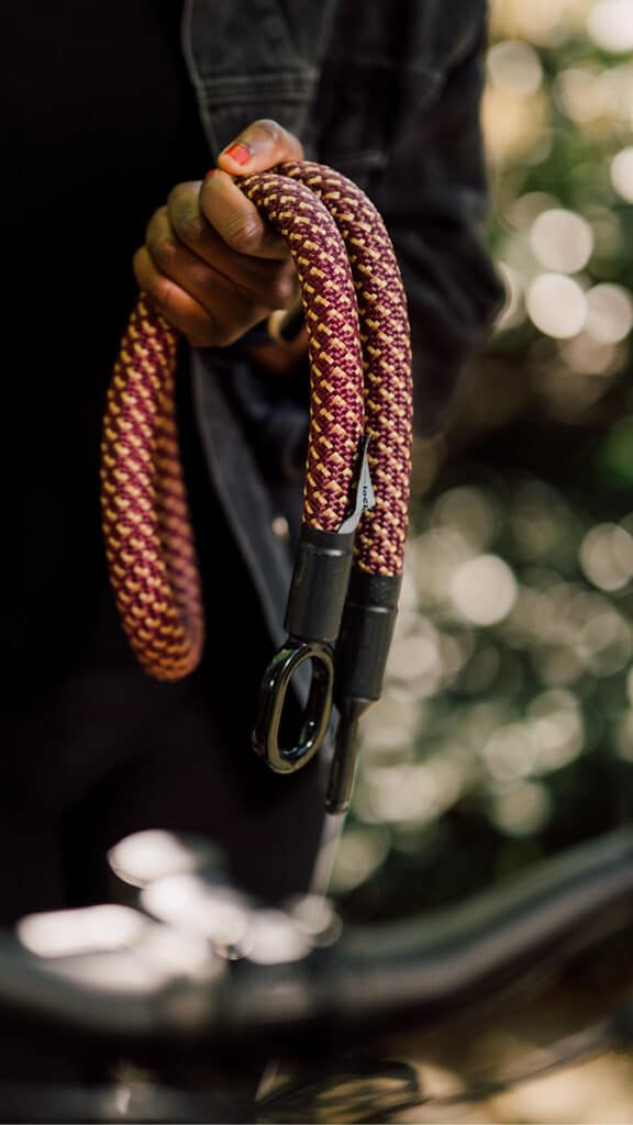 Weibliches Model hält tex–lock mate in chateau red in der Hand, Universalbolzen und gummierte Metallöse hängen nebeneinander