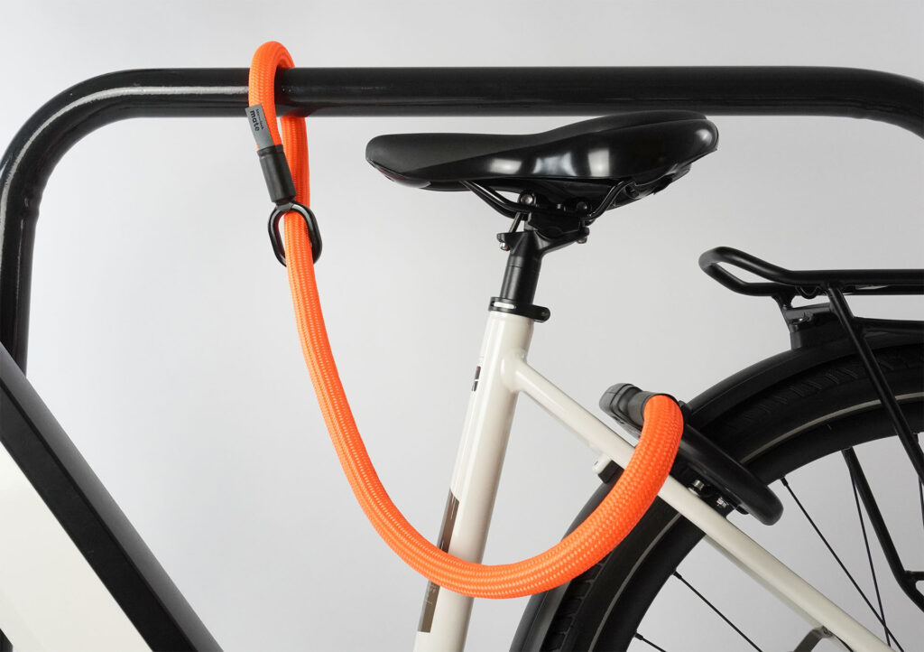 tex–lock mate in acid orange erweitert Rahmenschloss, indem es Fahrrad an Fahrradständer sichert