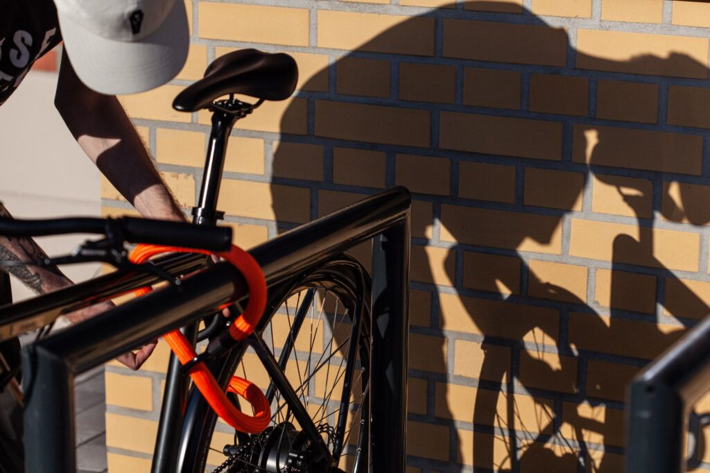 Fahrradfahrer schließt Rahmen und Hinterrad mit tex-lock eyelet orange an Fahrradständer an