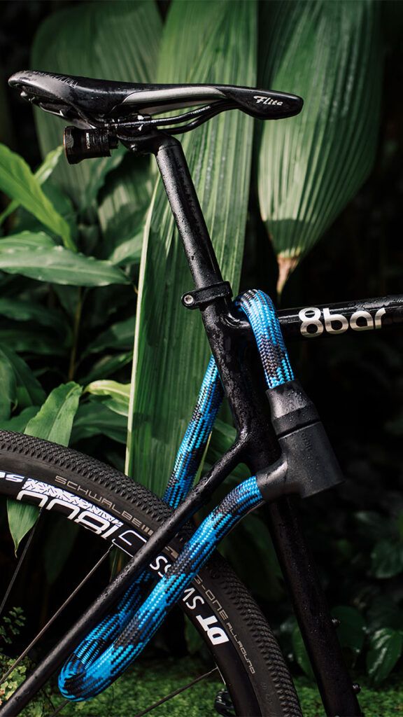 Blau-schwarzes Seilschloss aus Textil sichert schwarzes Fahrrad am Rahmen und Hinterrad ab