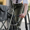 Frau schließt Fahrrad mit flexibler Rahmenschloss-Verlängerung tex-lock mate in grau am Pfosten an