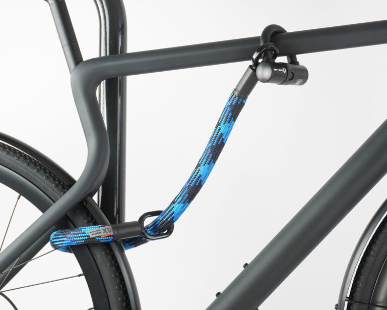 Hinterrad und Oberrohr vom Fahrrad mit Bügelschloss und Verlängerung aus Textil in blau-schwarz am Fahrradständer angeschlossen
