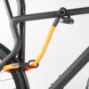 Hinterrad und Oberrohr vom Fahrrad mit Bügelschloss und Verlängerung aus Textil in orange am Fahrradständer angeschlossen