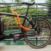 tex–lock eyelet in acid orange sichert schwarzes Lastenrad mit U-lock an Brückengeländer, Fluss im Hintergrund