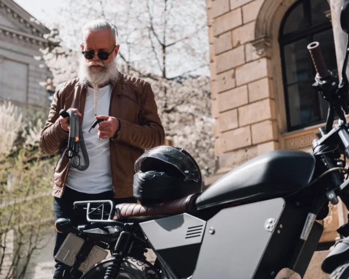 grau-schwarzes Textilschloss mit älterem male Model vor Motorrad