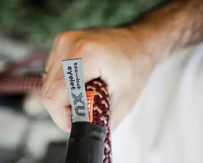 male model hält eyelet-Textilseil in chateau red mit Gummierung der Öse und Webetikett in der Hand