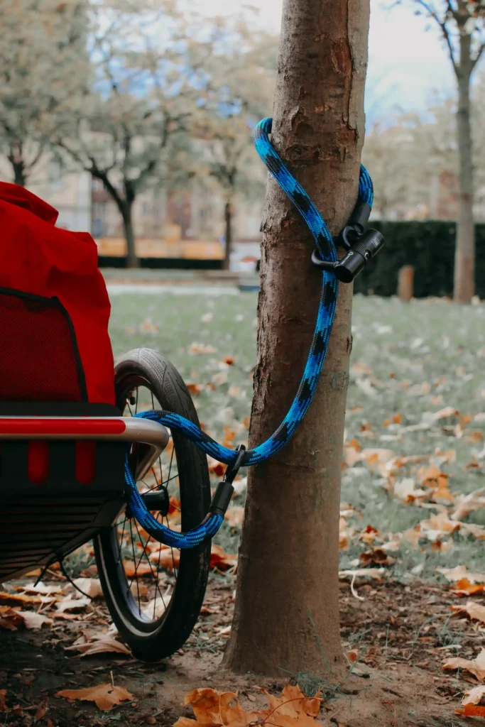 fahrradanhänger mit roter tasche am Baum angeschlossen mit blauem  Textilschloss