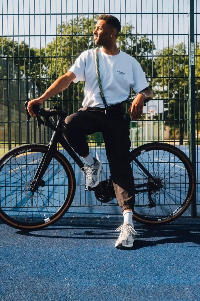 Mann in Tshirt und Jogginghose lehnt an Fahrrad mit tex–lock one spirit um der Schulter