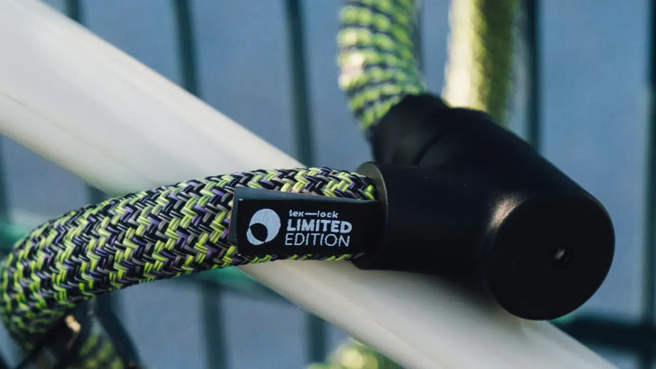 tex–lock orbit als Special Edition one spirit sichert weißen Fahrradrahmen an Zaun