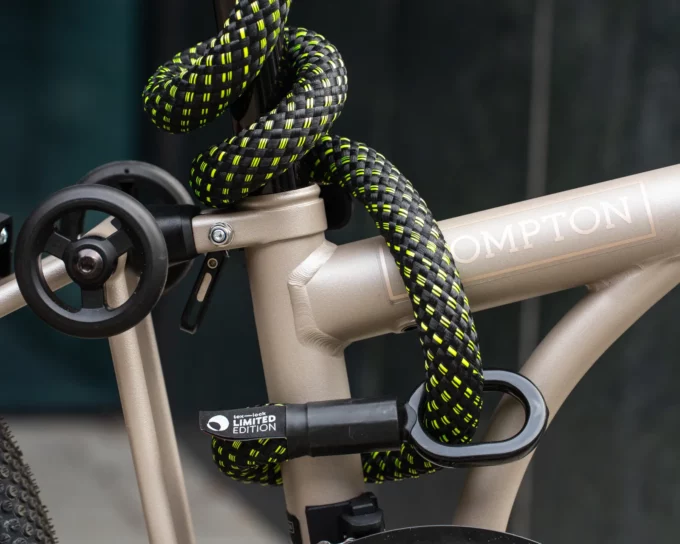 Schwarzes Fahrradschloss mit Neonfarben umschließt Brompton Faltrad