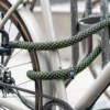 U/X-lock Bügelschloss an Sattelstrebe sichert Hinterrad und Fahrradrahmen mit flexiblem Textilseil an Zaun